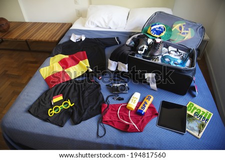 Suitcase packed for football referee trip to Brazil including red and yellow flags, whistle, camera, sunscreen, and guidebook
