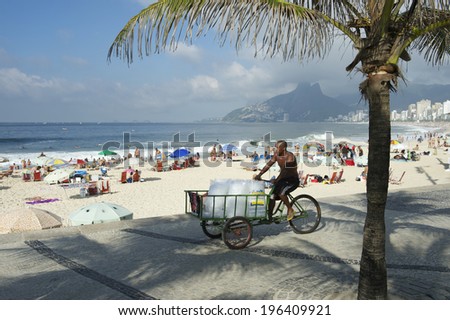 RIO DE JANEIRO, BRAZIL - JANUARY 19 2014: Vendor selling ice from a tricycle cart passes under palm shadows at Arpoador in Ipanema Beach.