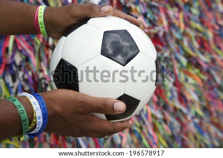 Brazilian man holding soccer ball football praying in front of Brazilian wish ribbons at the Bonfim church in Salvador Bahia Brazil