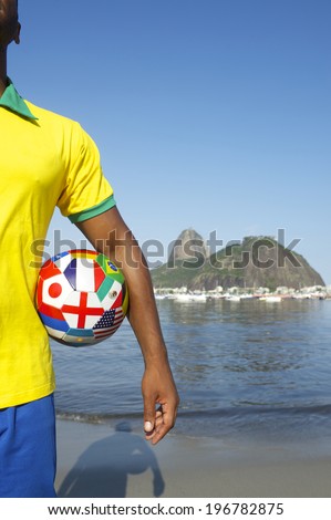 Brazilian football player standing with international country flag soccer ball in front of Sugarloaf Pao de Acucar Mountain and Guanabara Bay in Rio de Janeiro Brazil