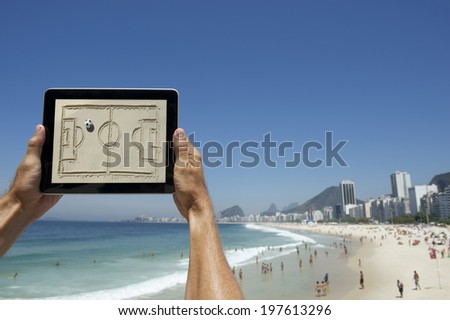 Hands holding digital football tactics board in front of Copacabana Beach Rio de Janeiro Brazil