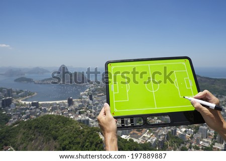 Hands holding soccer tactics board at Rio de Janeiro skyline