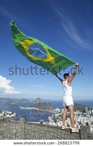 Olympic athlete in old-fashioned white sports uniform standing with Brazilian flag at city skyline overlook in Rio de Janeiro Brazil
