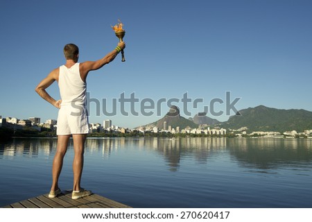 Young athletic man standing with sport torch against Rio de Janeiro Brazil skyline at Lagoa lagoon