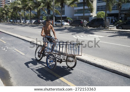 RIO DE JANEIRO, BRAZIL - FEBRUARY 15, 2015: Brazilian man rides cart to refill with bags of ice to be delivered to beach stalls along the Ipanema Beach boardwalk.