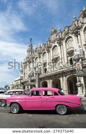 HAVANA, CUBA - JUNE, 2011: Bright pink vintage American car stands parked in front of the landmark architecture of the Great Theater of Havana.