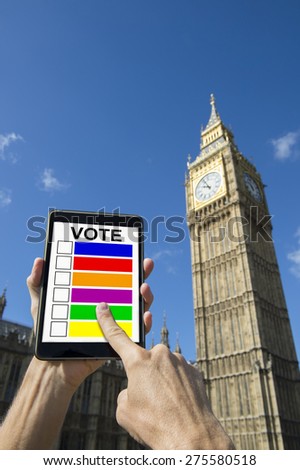 Finger of voter choosing candidates on digital tablet computer outside Big Ben Westminster Palace London under bright blue skies