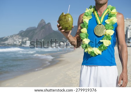 Gold medal athlete wearing gold medal celebrating with coconut on Ipanema Beach Rio de Janeiro Brazil