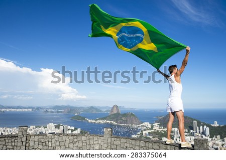 Athlete in old-fashioned white sports uniform standing with Brazilian flag at city skyline overlook in Rio de Janeiro Brazil