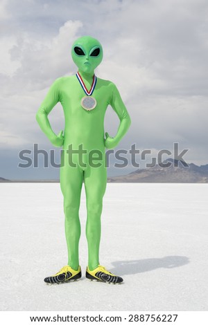 Green alien athlete wearing gold medal standing on stark white planet background