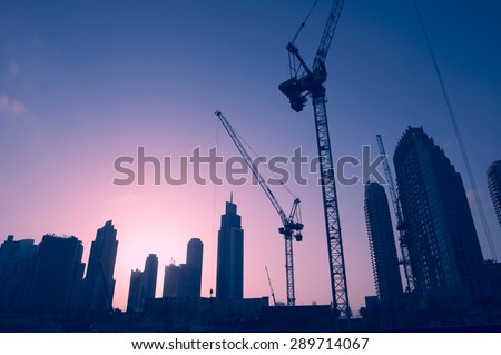 Sunset skyline of construction cranes amongst office tower skyscrapers in the Middle East center of trade, Dubai