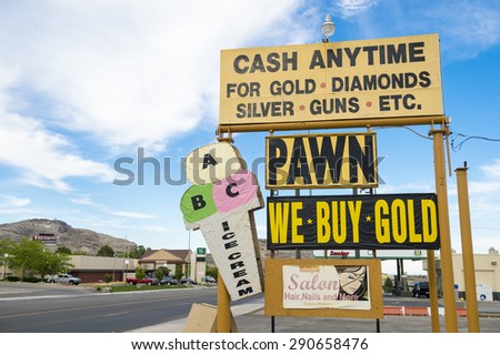 WENDOVER, NEVADA - AUGUST 18, 2013: Sign for American pawn shop advertises cash anytime for gold, diamonds, silver, and guns in the parking lot of an American roadside strip mall.