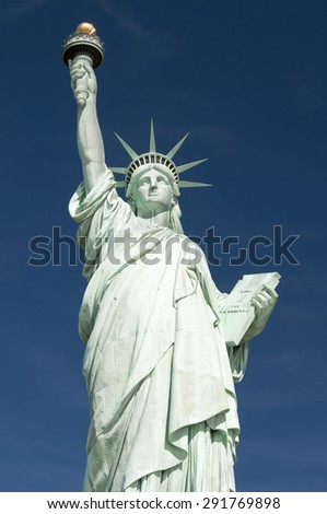 Front view of the Statue of Liberty holding her torch against bright blue sky
