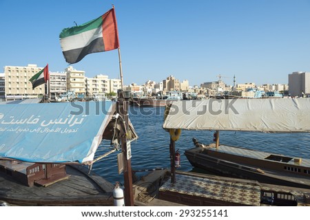 DUBAI, UAE - OCTOBER 22, 2015: UAE flag on the Bur Dubai side of the Creek flies over a pier for the traditional abra ferry boat to Deira.