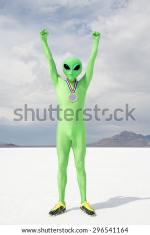 Green alien athlete wearing gold medal standing with arms raised on stark white planet background
