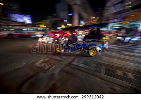 Bangkok Thailand tuk-tuk taxi zooms by in a night blur