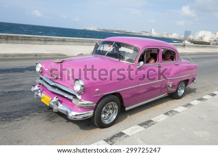 HAVANA, CUBA - MAY, 2011: Classic pink American taxi drives along the waterfront road of El Malecon in Central Havana.