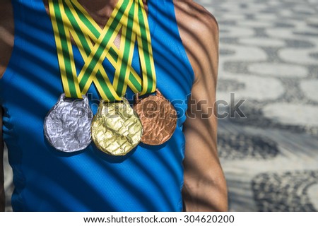Athlete wearing gold, silver, and bronze medals standing under palm frond shadows on Ipanema Beach