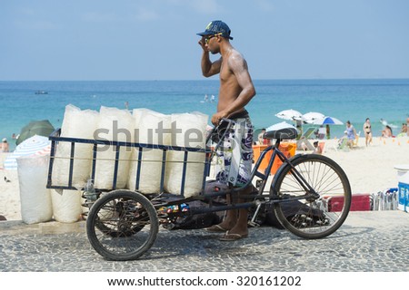 RIO DE JANEIRO, BRAZIL - FEBRUARY 22, 2015: Vendor stands with cart delivering bags of fresh ice to beach stalls on Ipanema Beach.