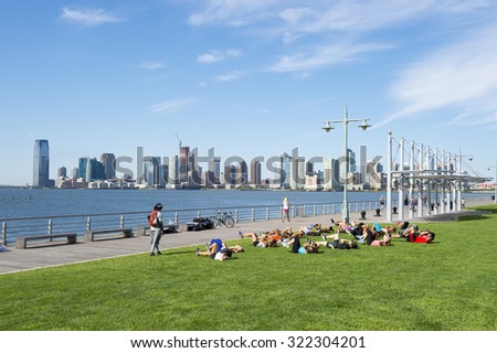 NEW YORK CITY, USA - AUGUST 29, 2015: Personal trainer leads group boot camp fitness class on the grass of a pier in the Hudson River Park.