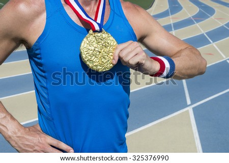 Athlete standing with gold medal and red, white, and blue ribbons at a blue and tan running track