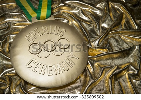 RIO DE JANEIRO, BRAZIL - FEBRUARY 3, 2015: Large gold medal commemorating the Opening Ceremony of the 2016 Olympic Games sits on shiny golden background.