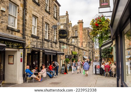 Harrogate, UK - September 27, 2014: People enjoying a warm Autumn day in a cobbled Street lined with Restaurant and Shops. Harrogate is consistently voted as one of the best places to live in the UK.