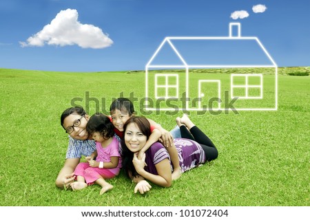 Asian happy family with dream house. Shot in meadow