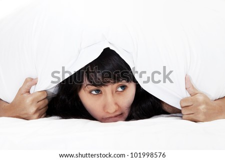 Scared Asian Woman hiding under a pillow with copy space available for your own text