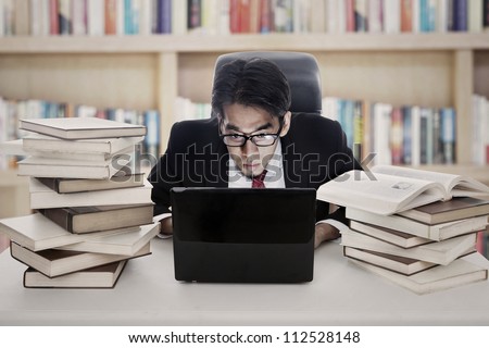 Portrait of asian employee works in library by using laptop computer