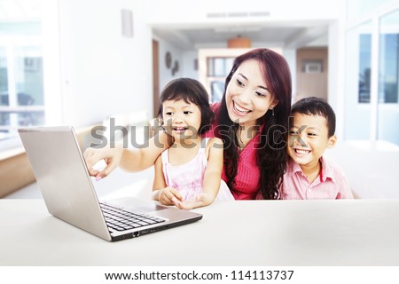 Happy young mother with her children using ultrabook laptop computer to enjoy entertainment at home