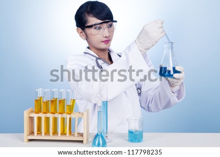 Female researcher working with blue chemical inside a flask