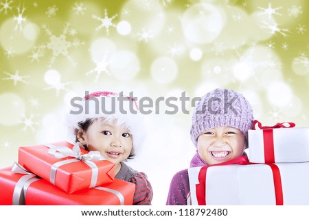 Brother and sister wearing hats are ready to open christmas gifts on defocused golden lights