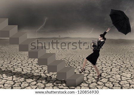 Businesswoman holding umbrella while walking up on stairs in stormy weather