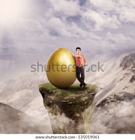 Businessman has golden egg on top of a mountain rock