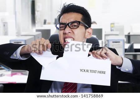 Angry Businessman ripping apart blank paper at the office