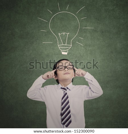 Little businessman thinking with eyes closed in class