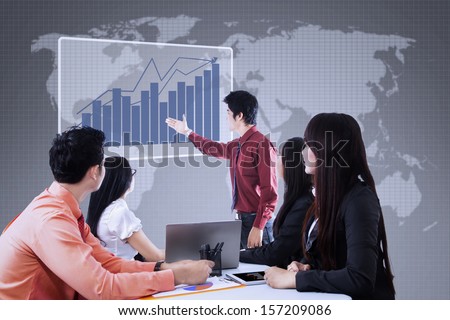 Business team is looking at bar chart on blue world map background