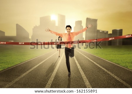 Business competition concept: Businessman crossing the finish line on the track