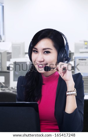 Female customer support operator with headset and smiling at office