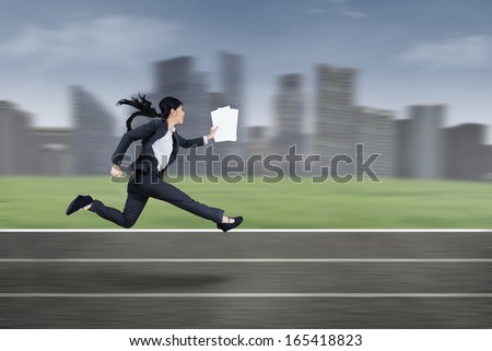 The young beautiful businesswoman runs by holding business paper