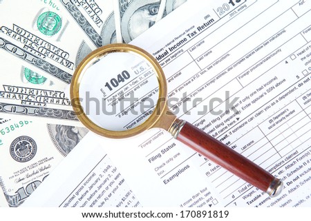 Tax audit concept with a magnifying glasses, tax form, and money