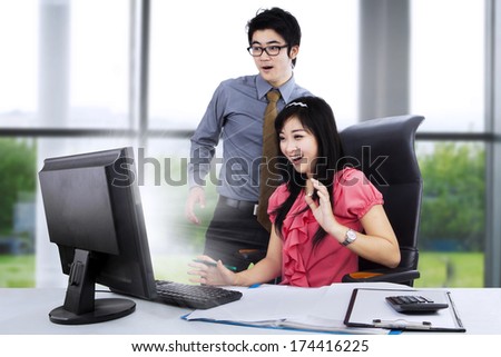 Young business couple shocked in front of computer on the desk