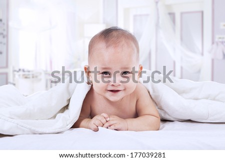 Baby laughing under blanket inside the house. shot in the bedroom