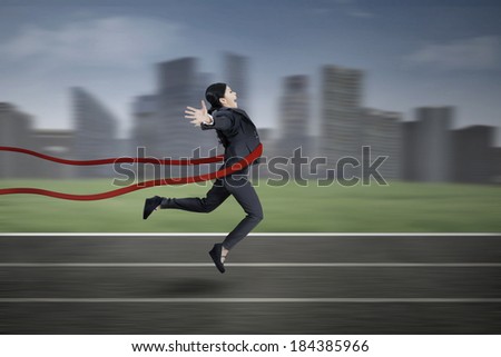 Businesswoman crossing the finish line with cityscape background