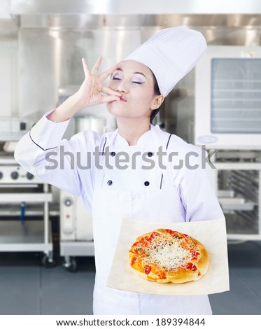 Beautiful Asian chef is serving delicious pizza in the kitchen
