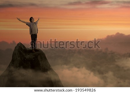 Success man on mountain peak enjoying freedom