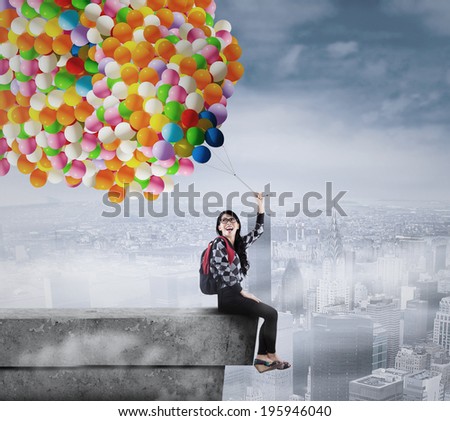 Female student holding a bunch of balloons on the rooftop