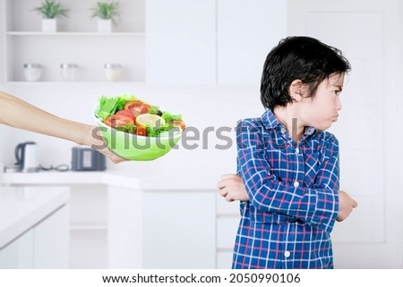 Little boy refusing a bowl of healthy salad while standing in the kitchen. Shot at home Foto stock © 