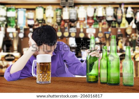 Drunk man sleeping in the bar, with bottle of beer in his hand